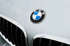 the front end of a silver bmw car with blue and white emblems on it