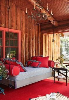 a bed with red pillows on top of it in a room filled with wooden walls