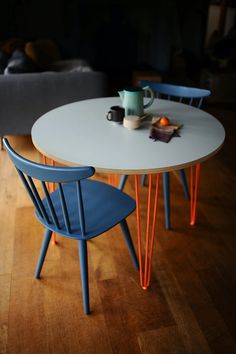 two chairs sitting at a table with a cup on it and an orange wire in the middle