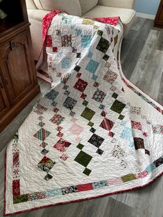 a white couch sitting next to a quilt on the floor