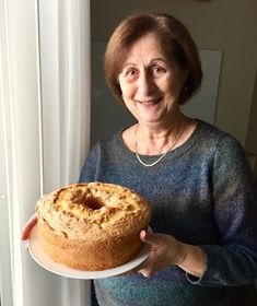 an older woman holding a cake on a plate