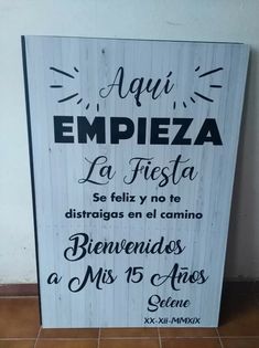 a sign that is on the ground in front of a wall with spanish words written below it