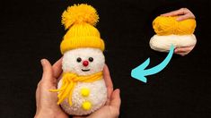 a hand holding a small white stuffed animal with yellow pom - poms on it's head