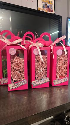 four pink bags with bows on them sitting on a table in front of a computer