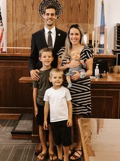 a man in a suit and tie standing with two women and three children, all smiling for the camera