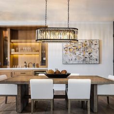 a dining room table with white chairs and a chandelier hanging from the ceiling