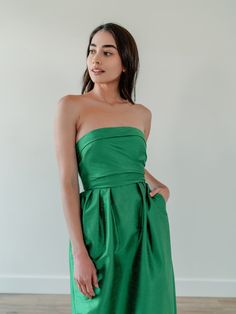 a woman in a green strapless dress poses for the camera with her hands on her hips