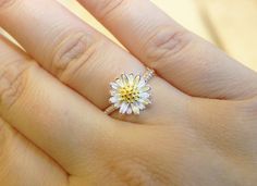 a woman's hand with a yellow and white daisy ring on it