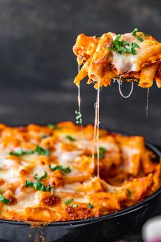 a slice of cheesy lasagna being lifted from a black casserole dish