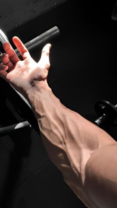 a person's arm and hand reaching for a barbell