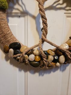 a wreath made out of rope with stones and moss on the front door handle for decoration