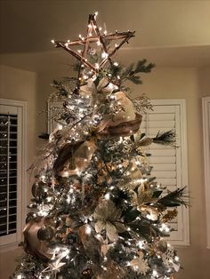 a decorated christmas tree in a living room with lights and ornaments on the top,