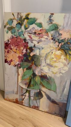 an oil painting of flowers in a vase on a wooden floor next to two books