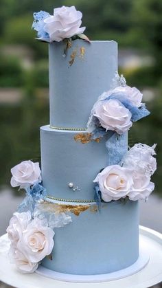 a three tiered blue wedding cake with white flowers