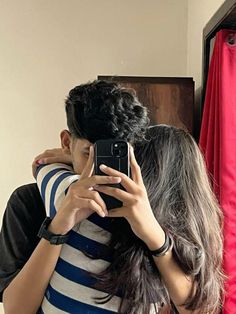 a man and woman taking a selfie in front of a mirror with their arms around each other