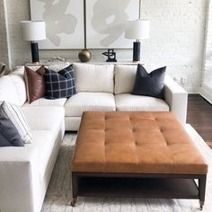 a living room with white couches and pillows on the floor in front of two large paintings