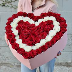 a woman holding a heart shaped box filled with roses