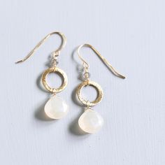 Pretty and simple, these little gems will be your go-to earrings. - White chalcedony gemstones- 1.5" long- French hooks - 14k gold plated .925 fine Italian sterling silver- Made in the USA in our NYC studio- Packaged in a gift box- Free shipping on US orders Handmade to last. Our unique gold plating technique makes our jewelry tarnish resistant. The nature of natural gemstones makes each style one-of-a-kind. Dangle Earrings Wedding, Chalcedony Earrings, Minimalist White, Wrapped Earrings, Gemstone Jewelry Handmade, Wire Wrapped Earrings, Silver Drop Earrings, Gold Drop Earrings, Kendra Scott