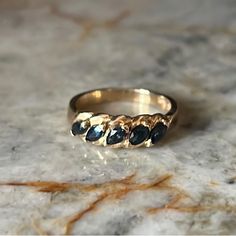 a close up of a gold ring with black stones on the inside and outside, sitting on a marble surface