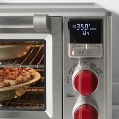 a pizza is cooking in an oven with red knobs