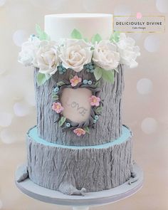 a cake decorated with flowers and leaves on top of a tree stump, in the shape of a heart