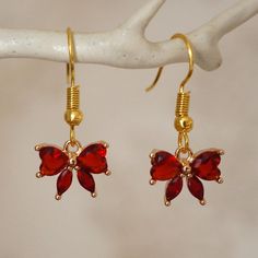 Make a statement with these pretty red bow drop earrings for women. These cool quirky gold plated and rhinestones bow earrings are a great way to add a nice touch to your outfit. The charm on these bow dangle earrings measures at 1.2cm x 1cm and is attached to a gold plated hook. Please feel free to get in touch with us at Funky Earrings UK if you have any questions. We also have a wide range of other cute and unusual earrings in our shop. Valentine's Day Jewelry With Red Bow, Elegant Red Jewelry With Bow, Earrings Cool, Red Flower Earrings, Funky Earrings, Unusual Earrings, Gold And Red, Rhinestone Bow, Bow Earrings