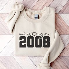 a white sweater with the words vintage in black on it, sitting on a wooden floor