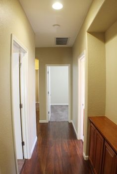 an empty hallway with hard wood floors and white walls