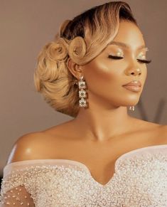 a woman in a white dress with her hair styled into a high bun and earrings