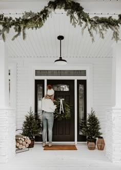 a woman standing in front of a door holding a wreath