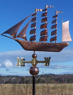 a weather vane with a sailboat on it in the middle of an open field