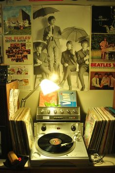 a record player sitting on top of a table next to a wall covered in posters