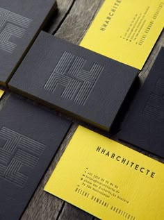 black and yellow business cards sitting on top of a wooden table