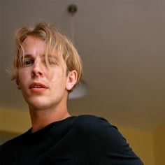 a man with blonde hair is staring into the distance while wearing a black t - shirt