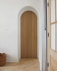 an arched wooden door in a white room