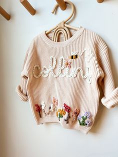 a pink sweater that says hello with flowers on it