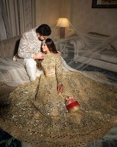 a man kneeling down next to a woman in a wedding dress on a bed covered with gold sequins