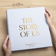 the story of us book being held by someone's hands on a wooden table