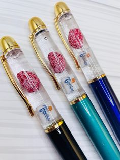 three fountain pens sitting next to each other on top of a white table with gold trimming