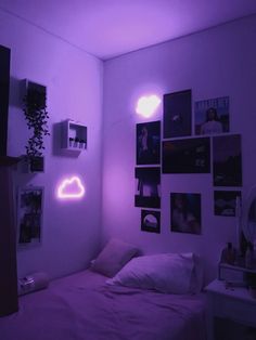 a bedroom with purple lighting and pictures on the wall above the bed in front of it