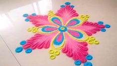 a pink and blue flower is on the floor with some buttons in front of it