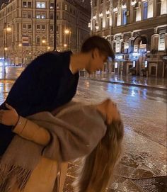 a man and woman standing on the street in the rain with their arms around each other