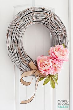 a wreath with pink flowers hanging on the front door