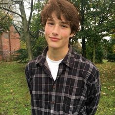 a young man standing in front of some trees