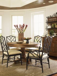 a dining room table with chairs and a vase filled with flowers on top of it