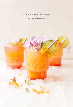 three glasses filled with drinks and garnished with flowers on the rim, surrounded by ice