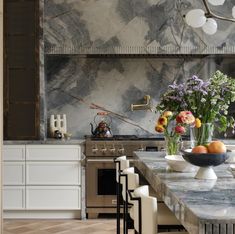 an elegant kitchen with marble counter tops and white chairs in front of the stove top