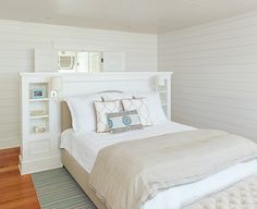 a bedroom with white walls and wood flooring has a large bed in the corner