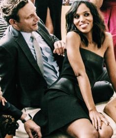 a woman in a black dress sitting next to a man wearing a suit and tie