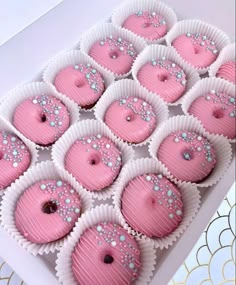 pink frosted cupcakes with white and blue sprinkles in a box